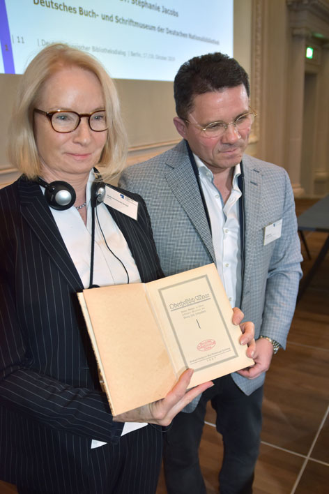Zwei Personen halten ein historisches Dokument in den Händen.