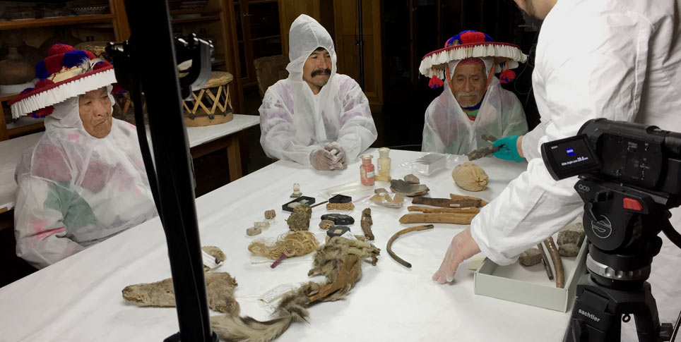 Eine Delegation von Wissensträgern der Huicholes, einer indigenen Gruppe aus Mexiko, ordnet die Sammlung von Ritualgegenständen ihrer Vorfahren im Ethnologischen Museum wieder zurück in die korrekte Anordnung. Diese war im Lauf der Zeit im Museum verloren gegangen