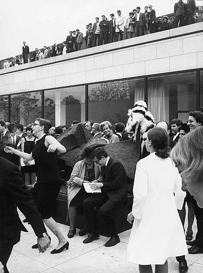 Schwarz-Weiß Fotografie mit mehreren Menschen, die vor und auf einem Gebäude tanzen und sich unterhalten (öffnet Vergrößerung des Bildes)
