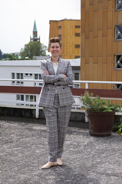 Eine Frau im Anzug steht auf dem Dach eines Gebäudes