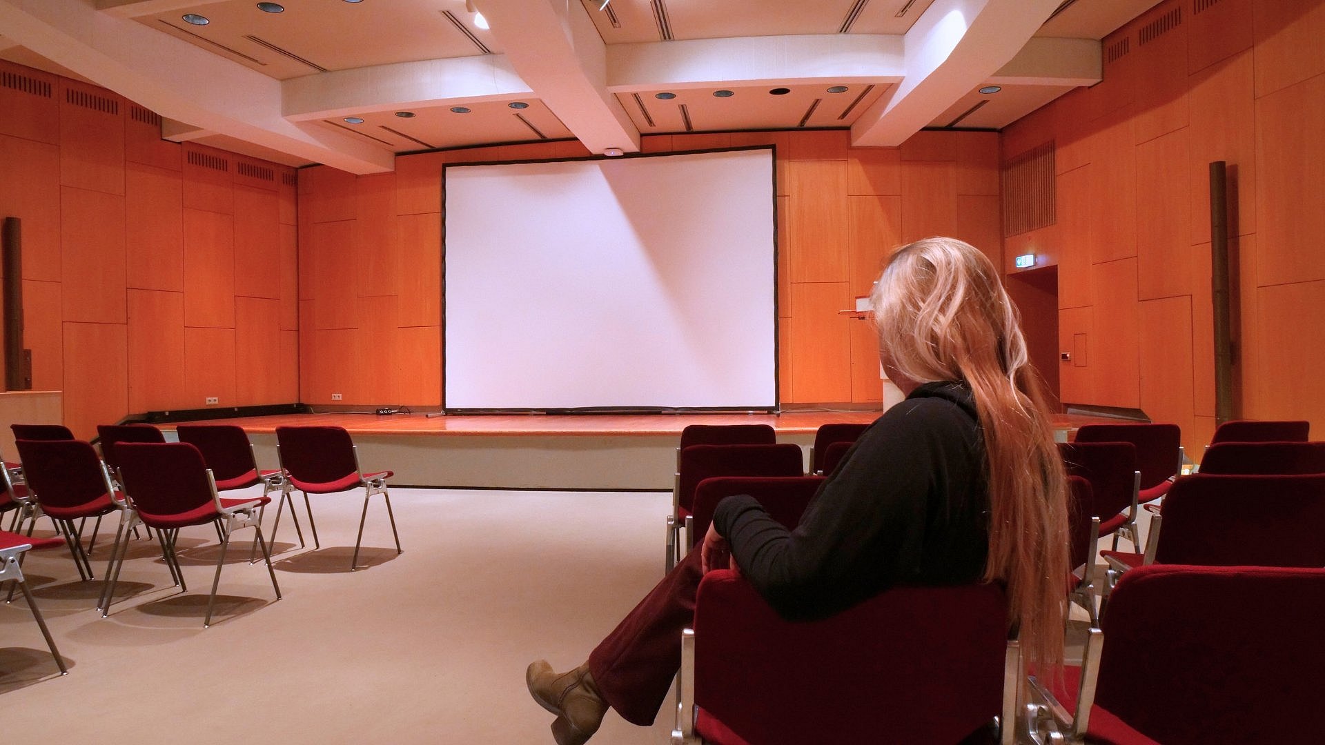 eine Frau sitzt auf einem Stuhl in einem Saal