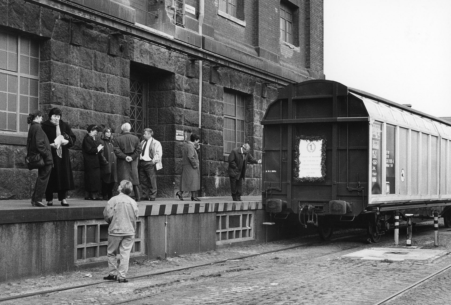 Schwarz-Weiß-Foto einer Menschengruppe neben einem Eisenbahnwaggon