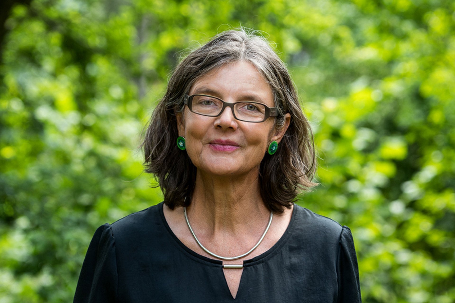 Porträt einer Frau mit Brille vor Bäumen