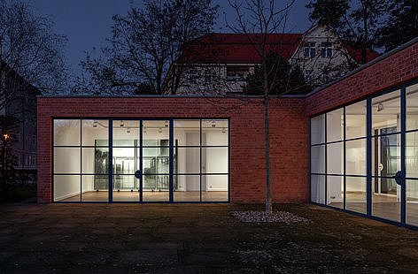 Ein modernes Gebäude mit großen Fenstern bei Nacht.