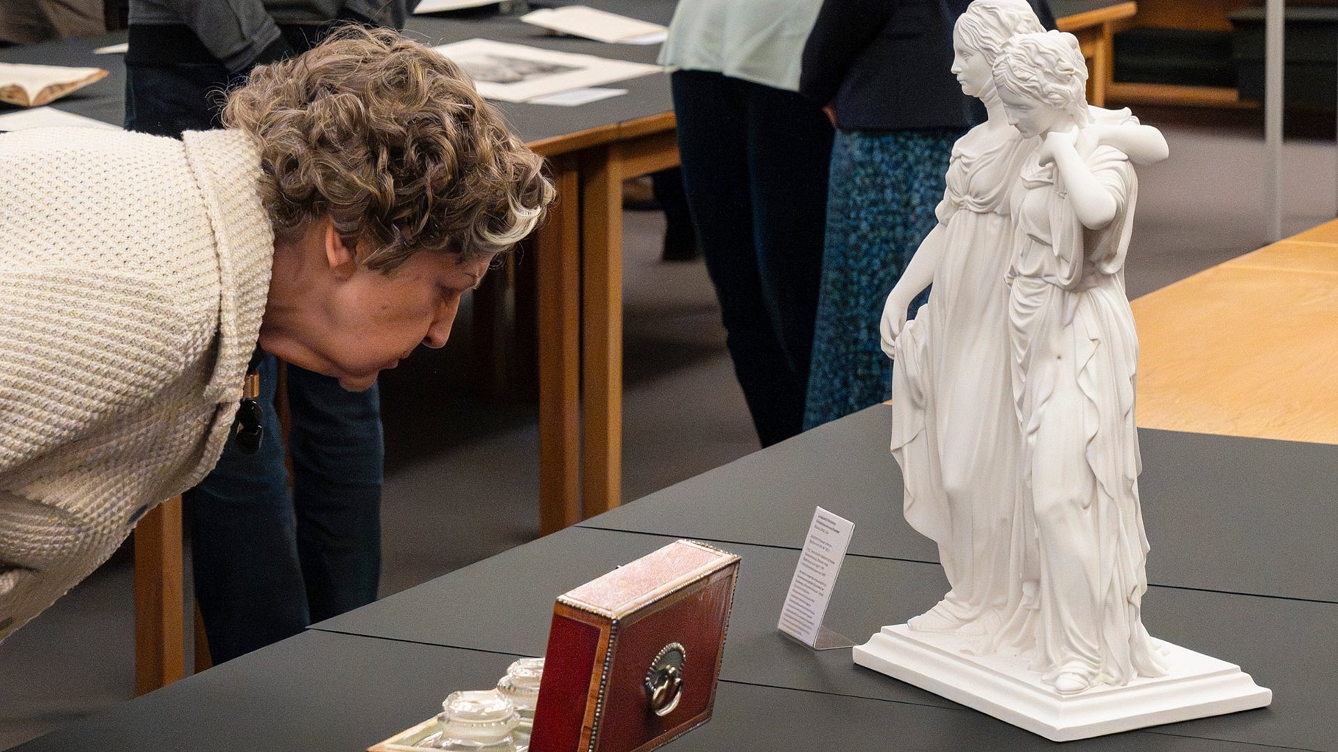 A woman is leaning over a casket on a table