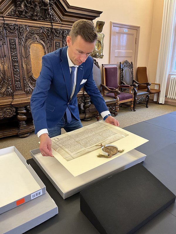 Johannes Götz mit den Urkunden des Deutschen Ordens im GStA; Foto: SPK/Stefan Müchler Ein Mann im Anzug beugt sich über mittelalterliche Dokumente