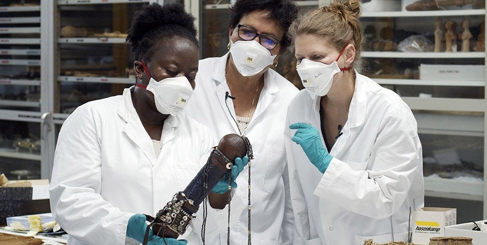 Drei Frauen in weißen Kasacks untersuchen ein Museumsobjekt