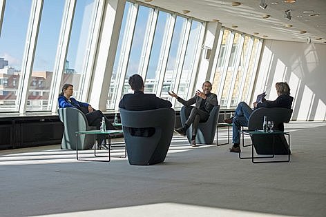 Drei Personen sitzen im Kreis auf Stühlen.