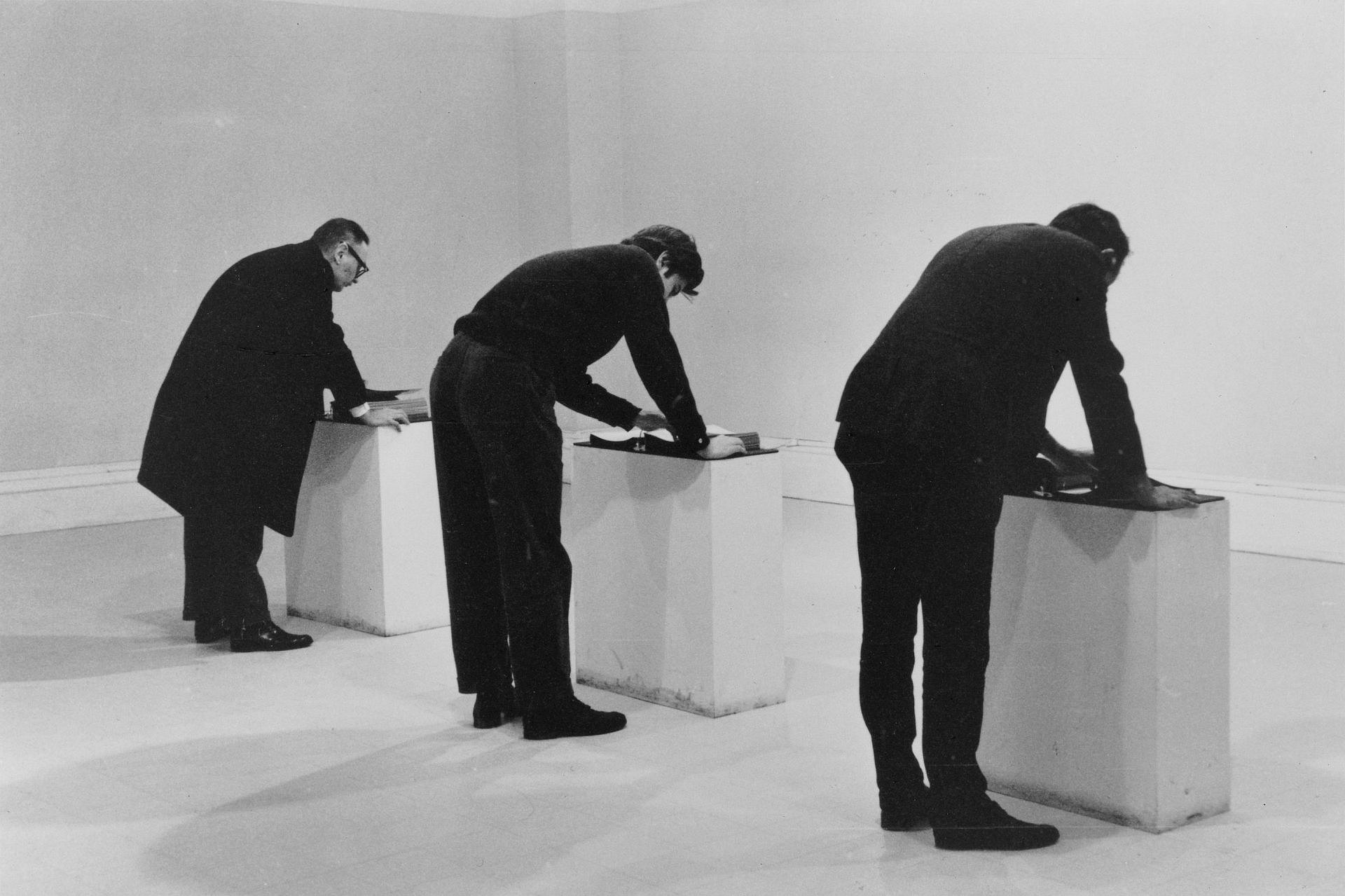 Drei Männer stehen jeweils an einem Ausstellungssockel