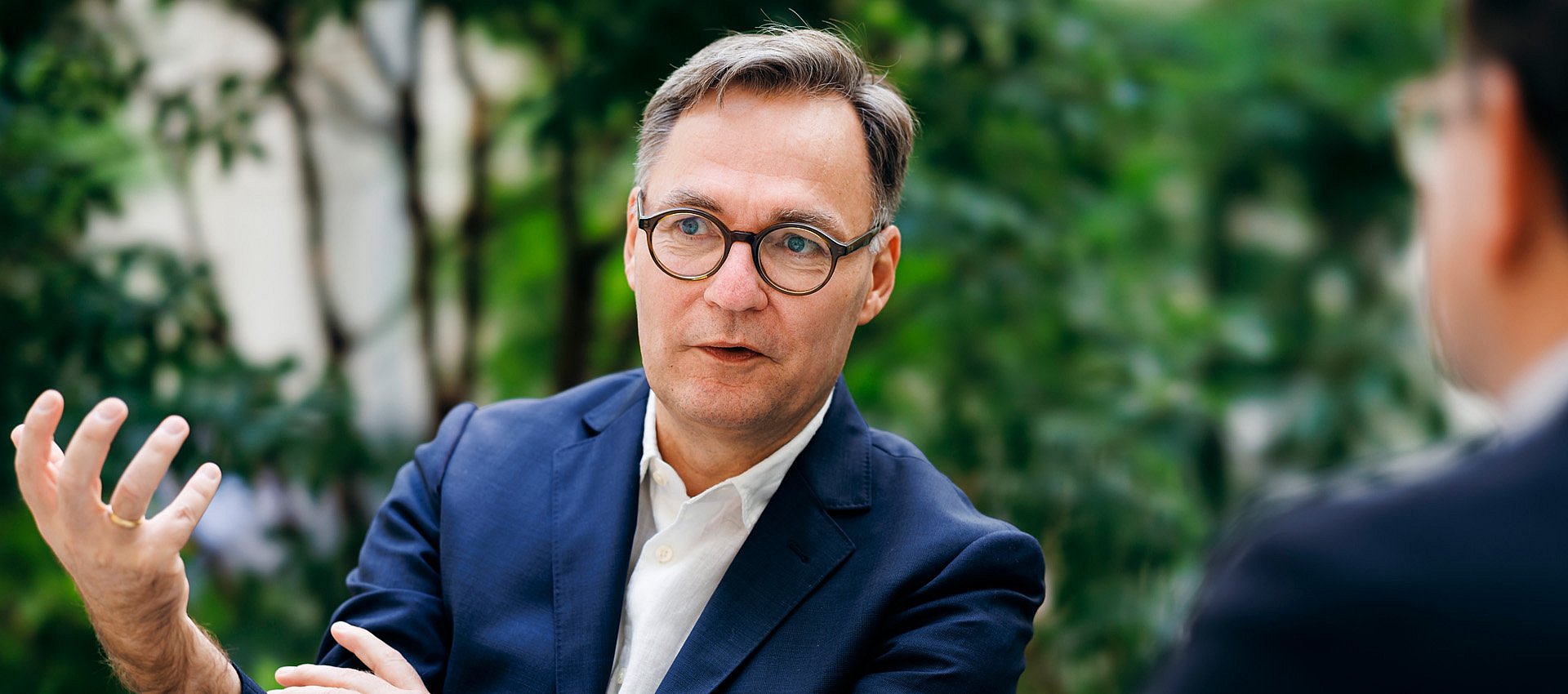 Ein Mann sitzt vor einer efeubewachsenen Wand
