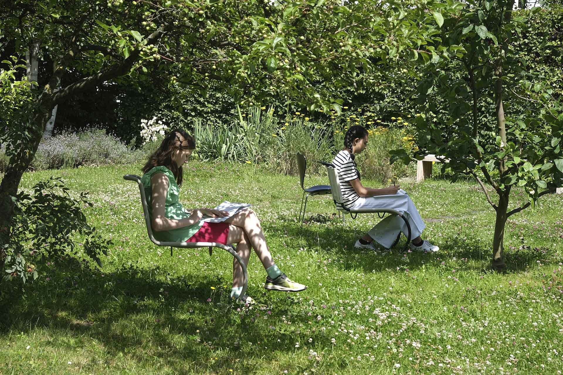 Zwei Kinder auf Stühlen im Garten
