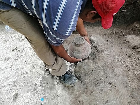 Ein Mann hebt ein Gefäß aus dem Boden