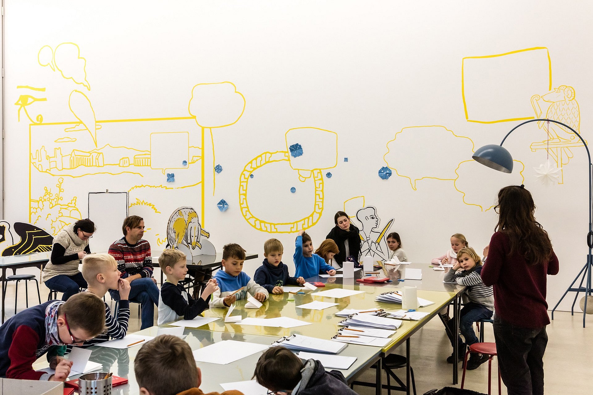 Schüler*innen sitzen an einem langen Tisch in einem Workshopraum