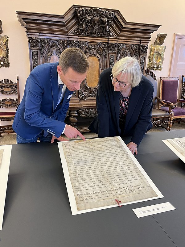 Johannes Götz und GStA-Direktorin Ulrike Höroldt begutachten die Urkunden des Deutschen Ordens; Foto: SPK/Stefan Müchler Ein Mann und eine Frau beugen sich über alte Pergamente