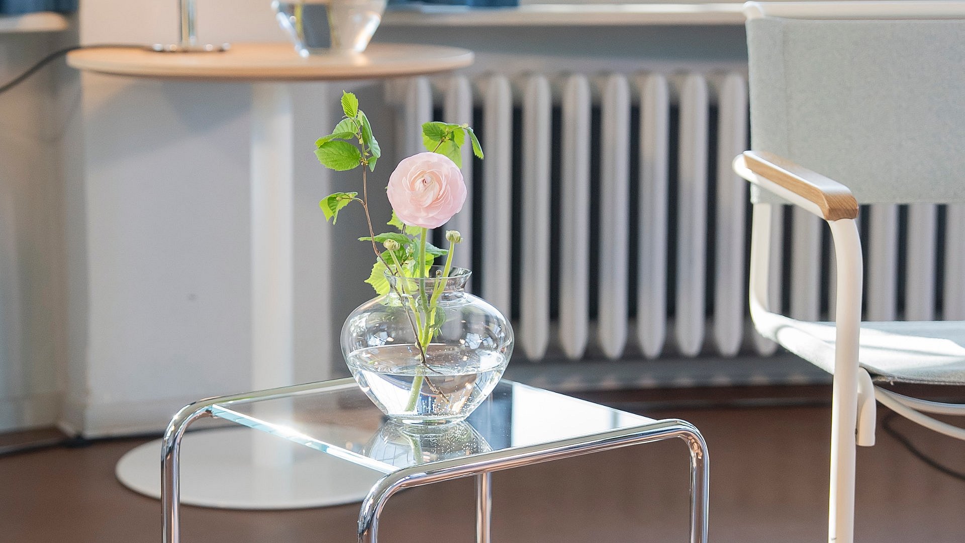 Glasvase mit rosa Blume auf Stahlrohrmöbeltischchen