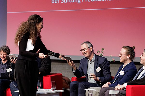 JE25 Frau gibt Karte an Mann