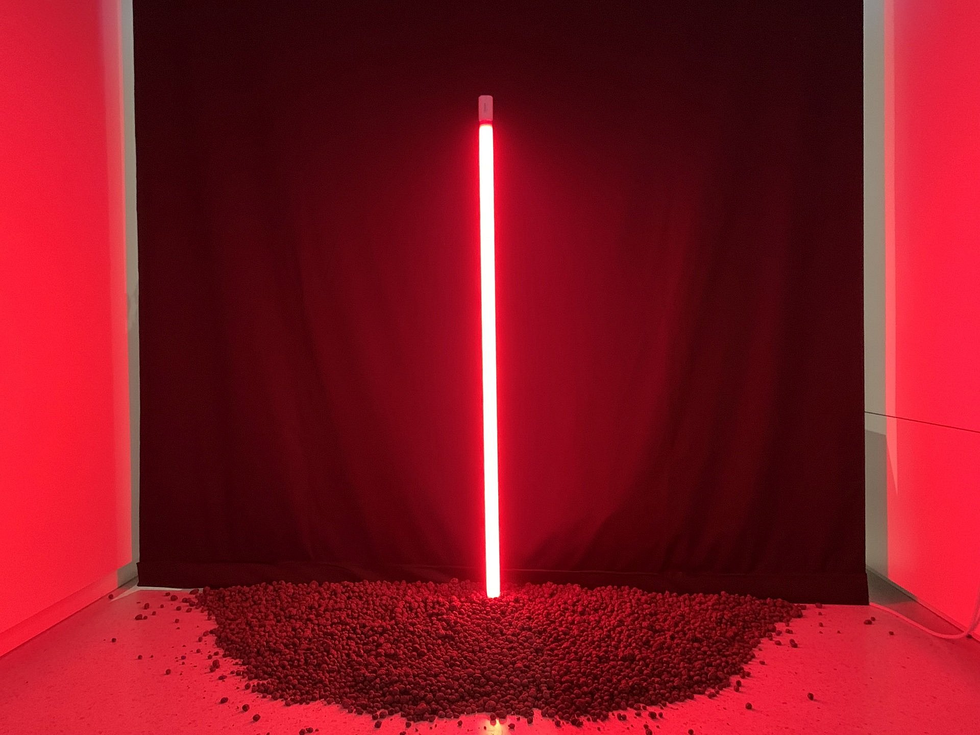 eine rote Neonröhre auf einem Kieshaufen