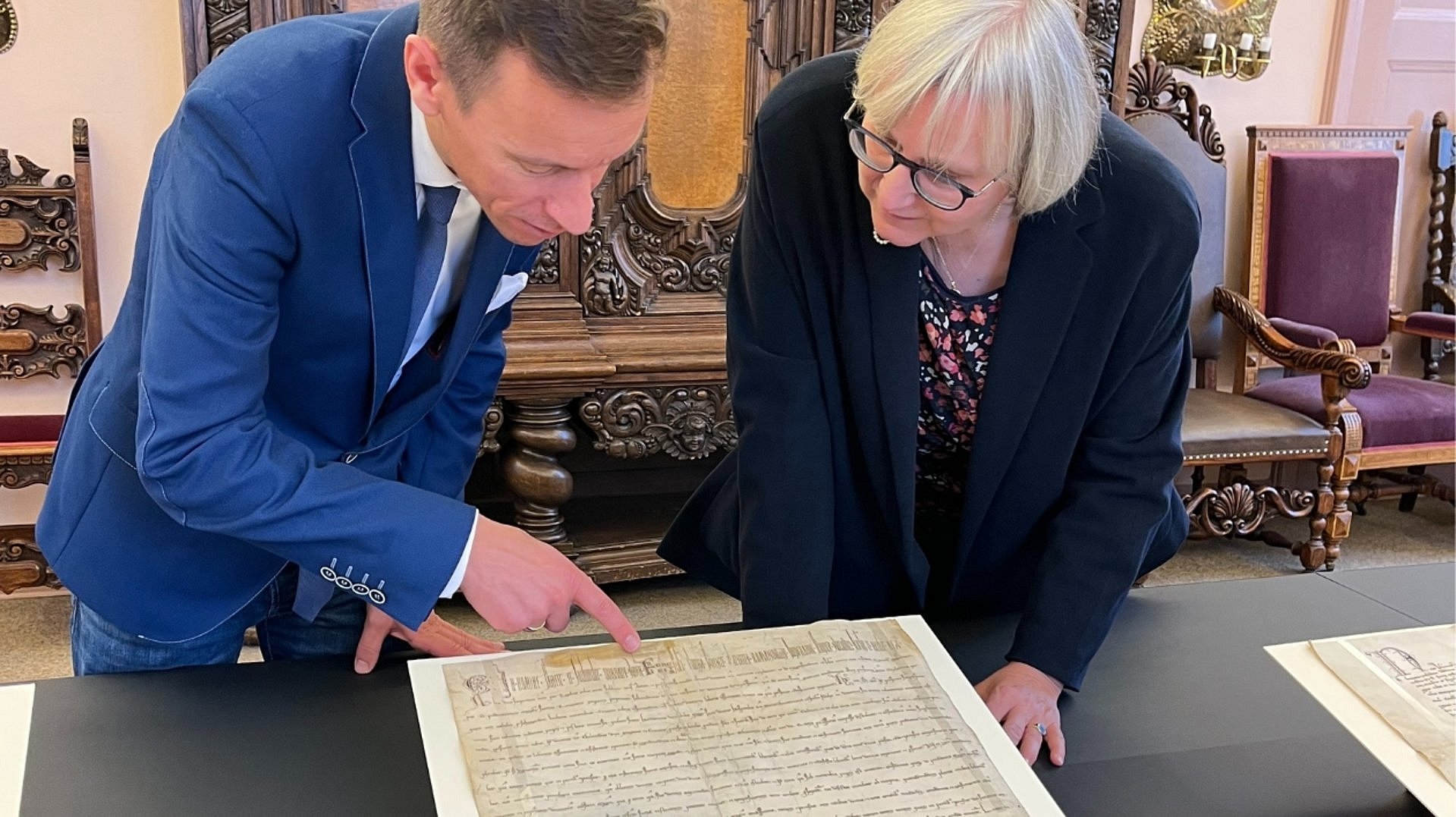 GStA-Archivar Johannes Götz und GStA-Direktorin Ulrike Höroldt betrachten gemeinsam eine historische Pergamenturkunde.