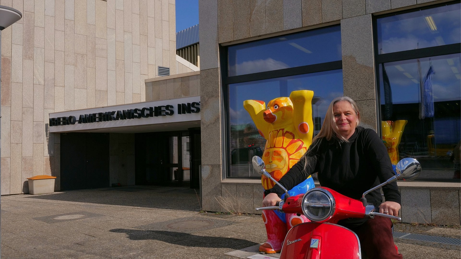 Eine Frau auf einer Vespa vor dem IAI