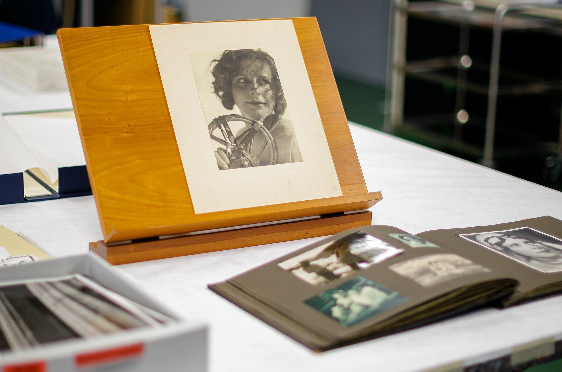 Porträtfoto einer Frau und ein aufgeschlagenes Fotoalbum auf einem Tisch