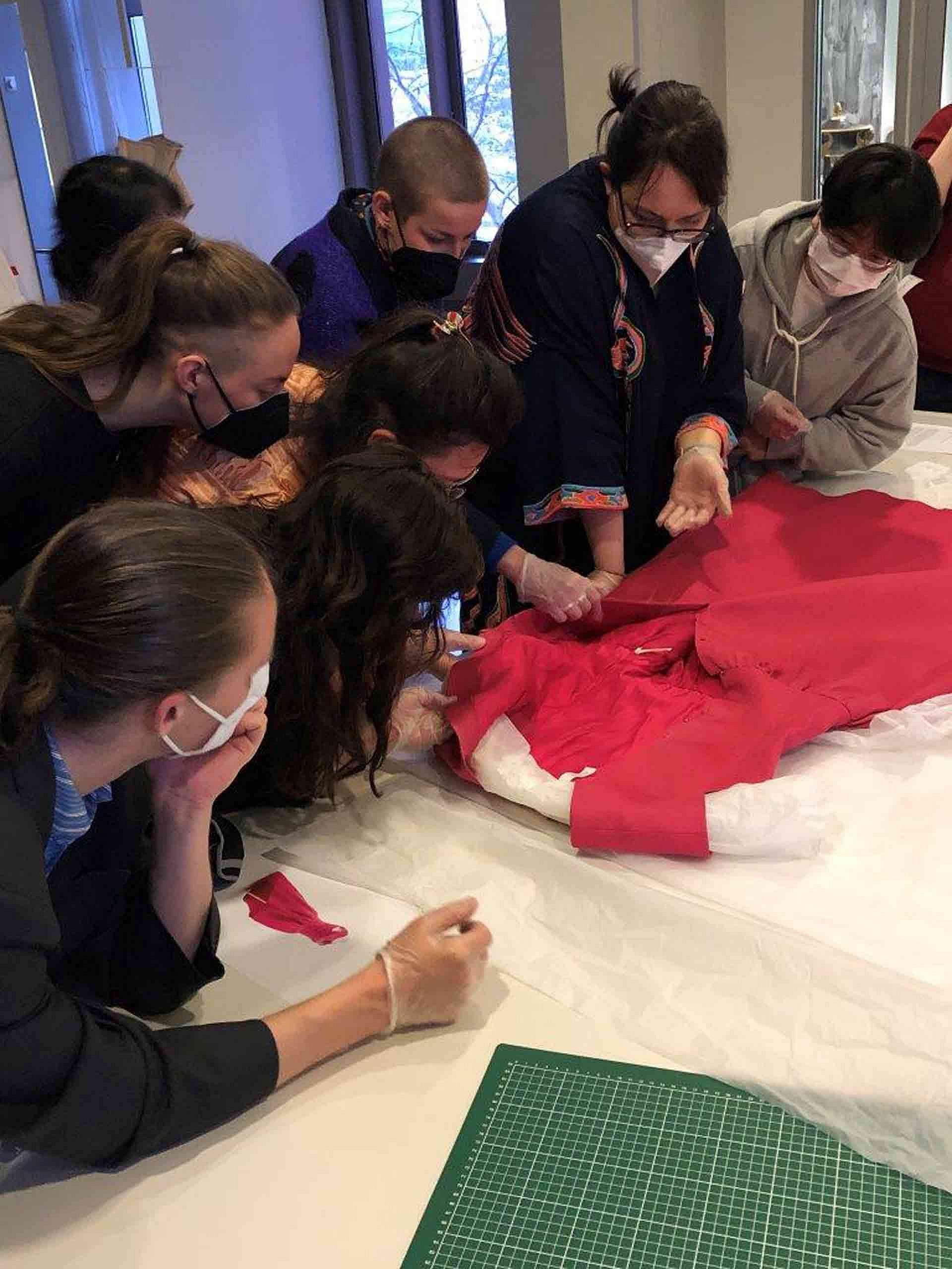 Personen beugen sich über ein rotes Kleid
