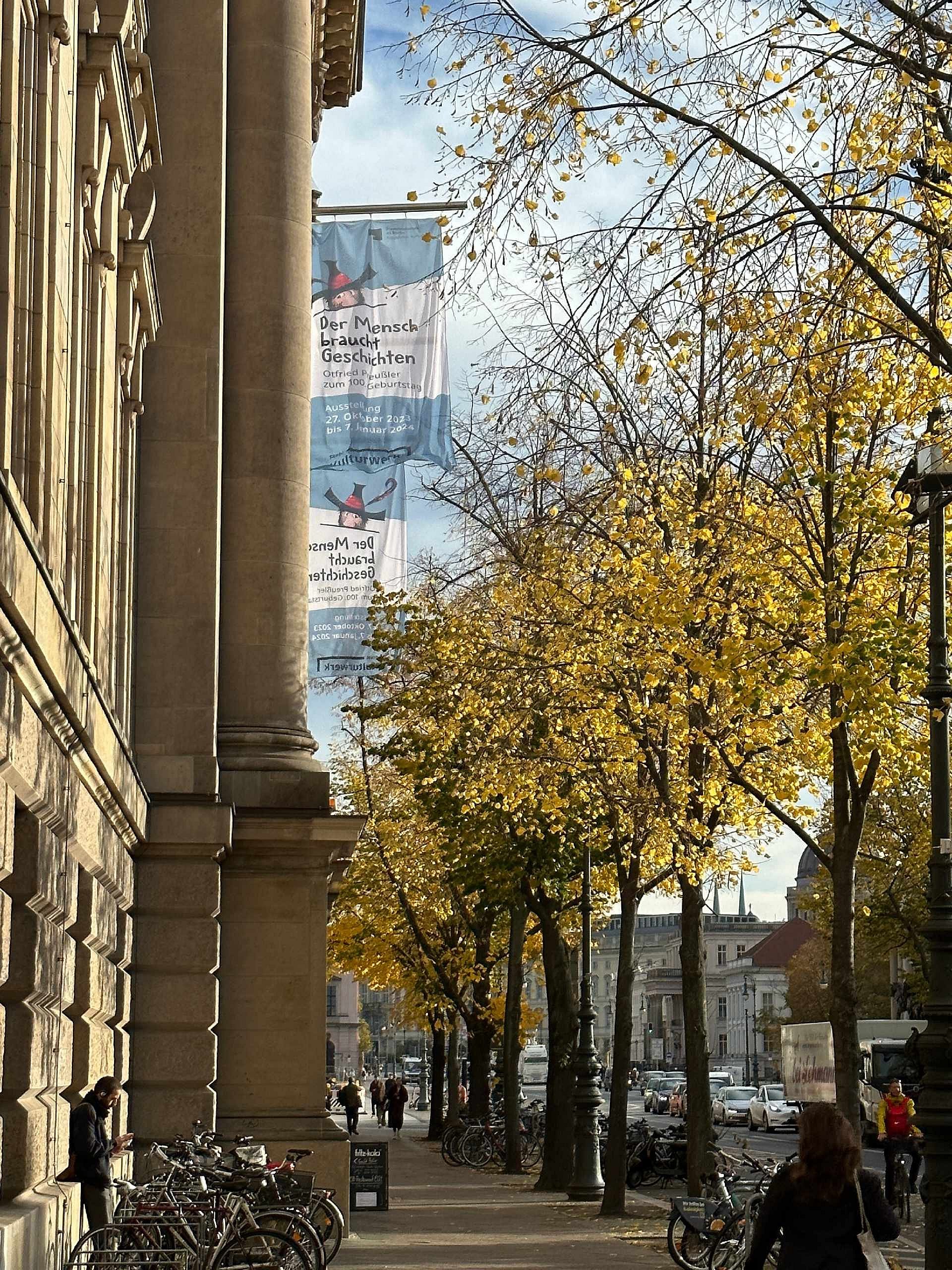 links: großese, altehrwürdiges Gebäude, rechts: Bäume mit Herbstlaub