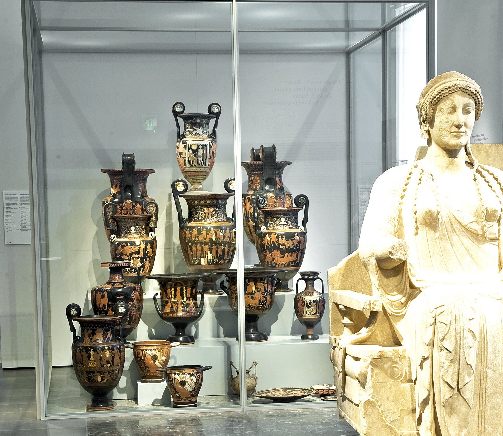 Blick auf eine Vitrine mit antiken Vasen, im Vordergrund eine antike Frauenstatue