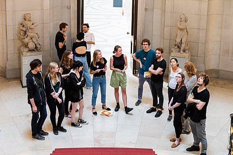 Mehrere Menschen stehen in einem Halbkreis in einer großen Halle