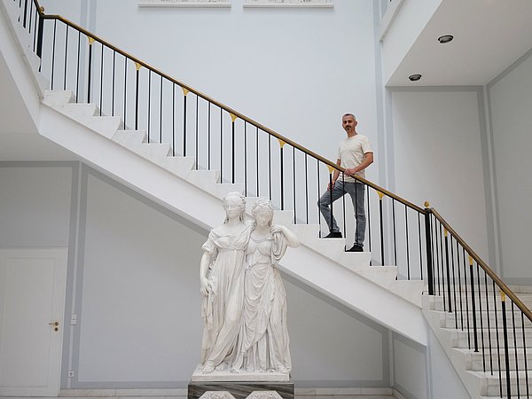 Mann steht auf Treppe hinter Marmorskulptur