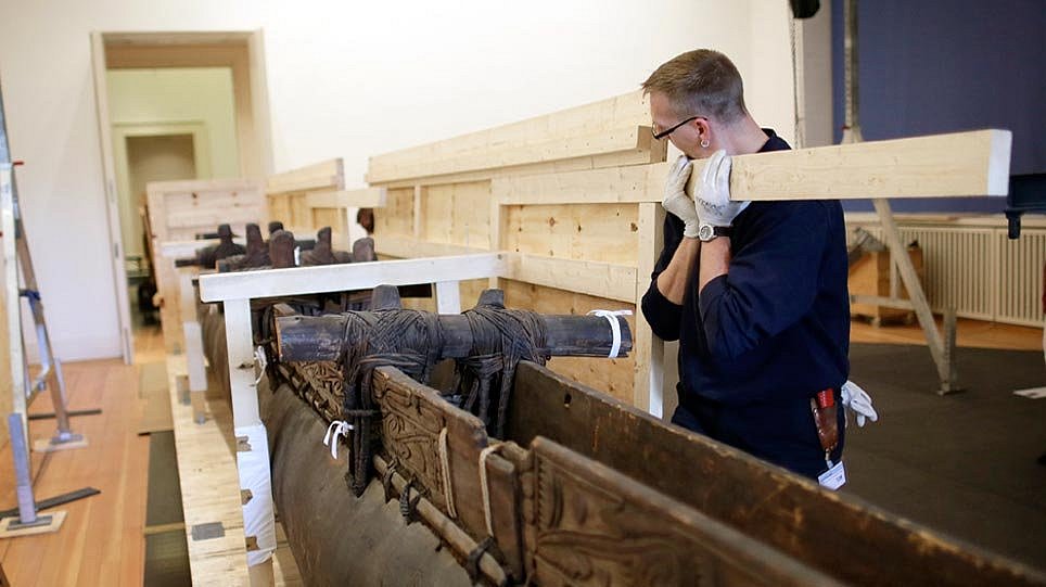 Ein Mann hält die Seitenwand einer Holzkiste, in der sich ein Boot befindet (öffnet Vergrößerung des Bildes)