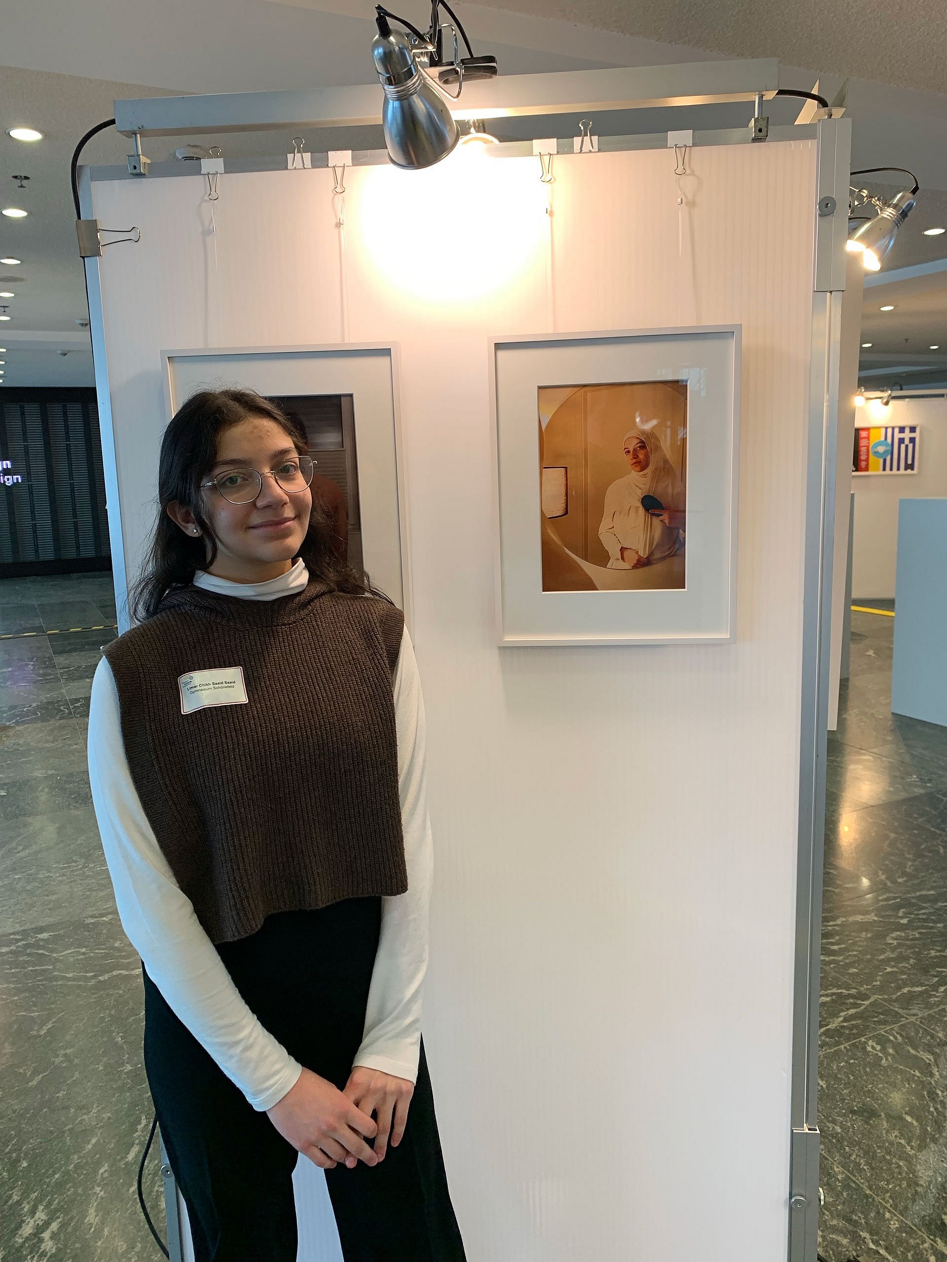 Junge Frau vor einer Fotografie an einer Stellwand