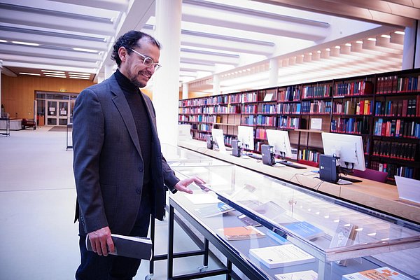 Carlos Nupia betrachtet im Lesesaal eine Vitrinen-Ausstellung Mann betrachtet Vitrine in einer Bibliothek
