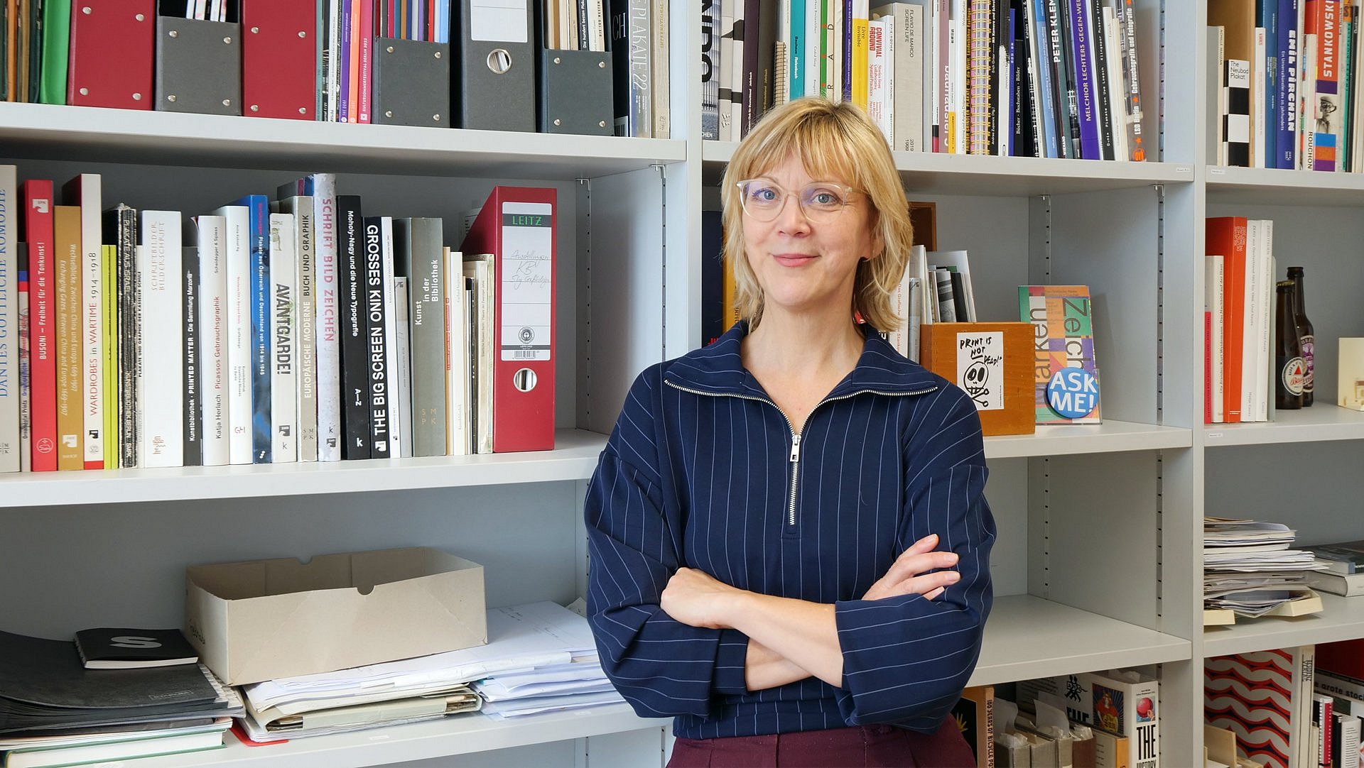 Eine Frau steht vor einem vollen Bücherregal