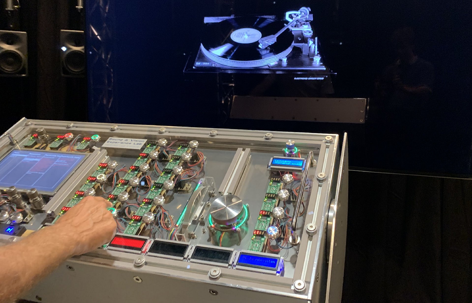 Der Arm einer Person bedient Knöpfe einer Schaltfläche vor einer Videoproduktion eines Schallplattenspielers