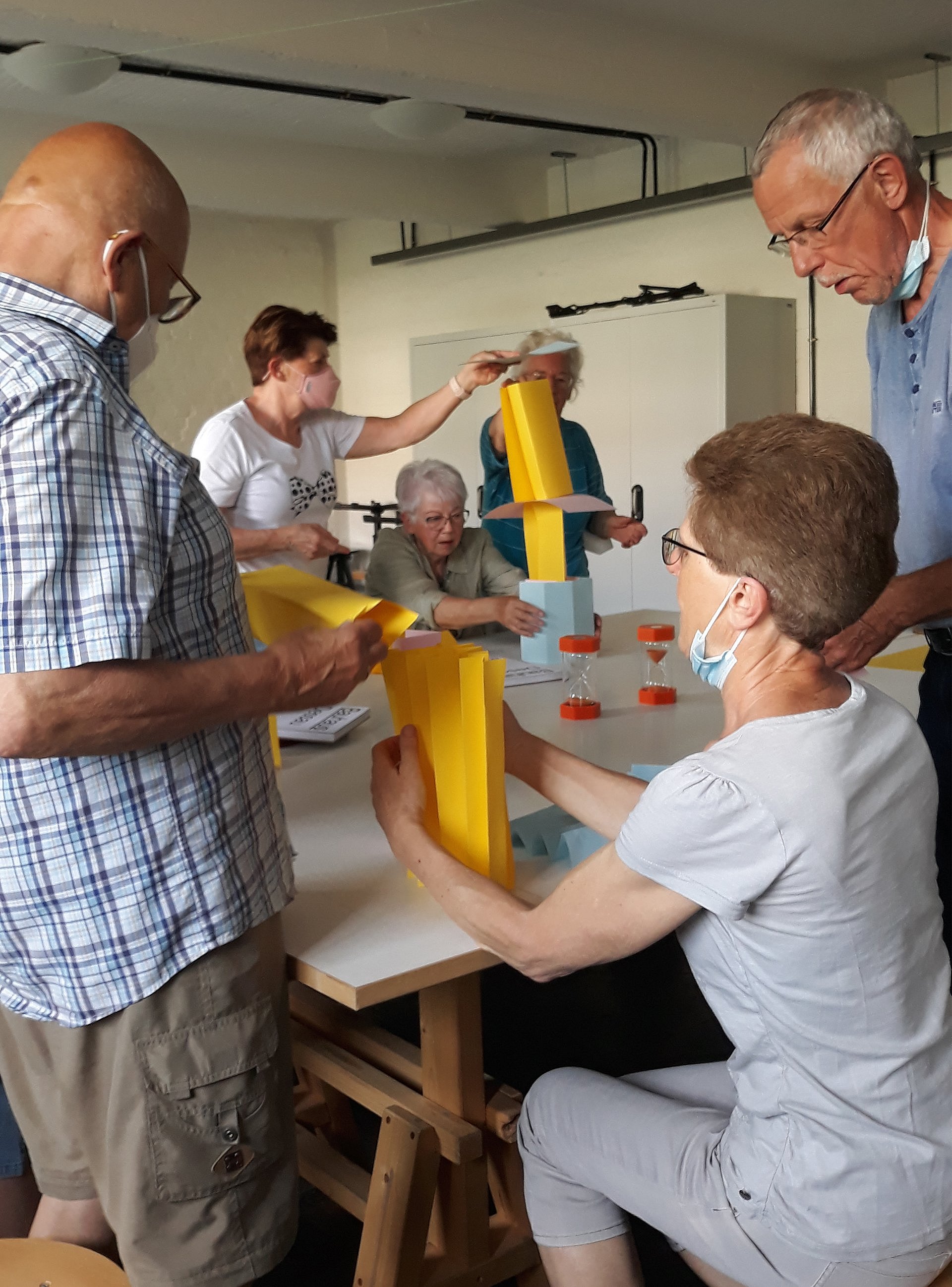 Vier ältere Leute bauen Skulpturen aus gelbem Papier