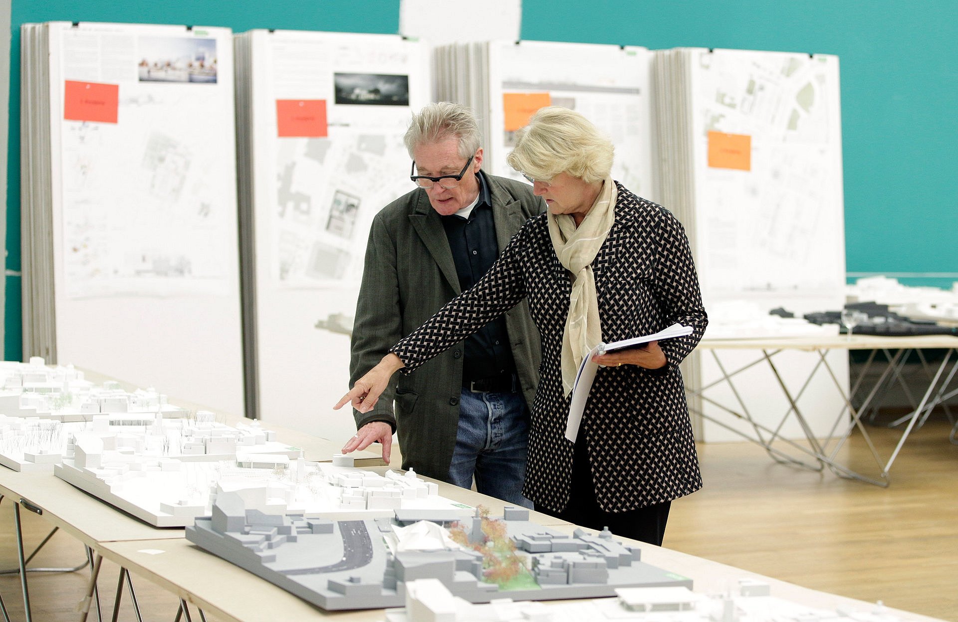 Ein Mann und eine Frau begutachten einen Tisch mit Architekturmodellen