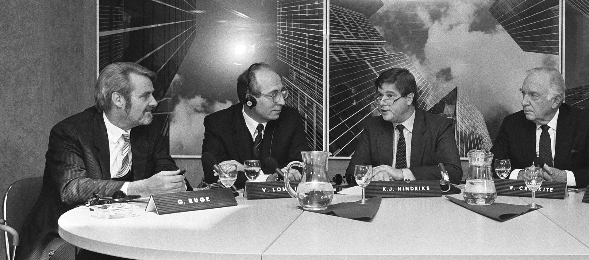 Schwarz-weiß Foto von vier Männern in Debattenrunde am Tisch sitzend