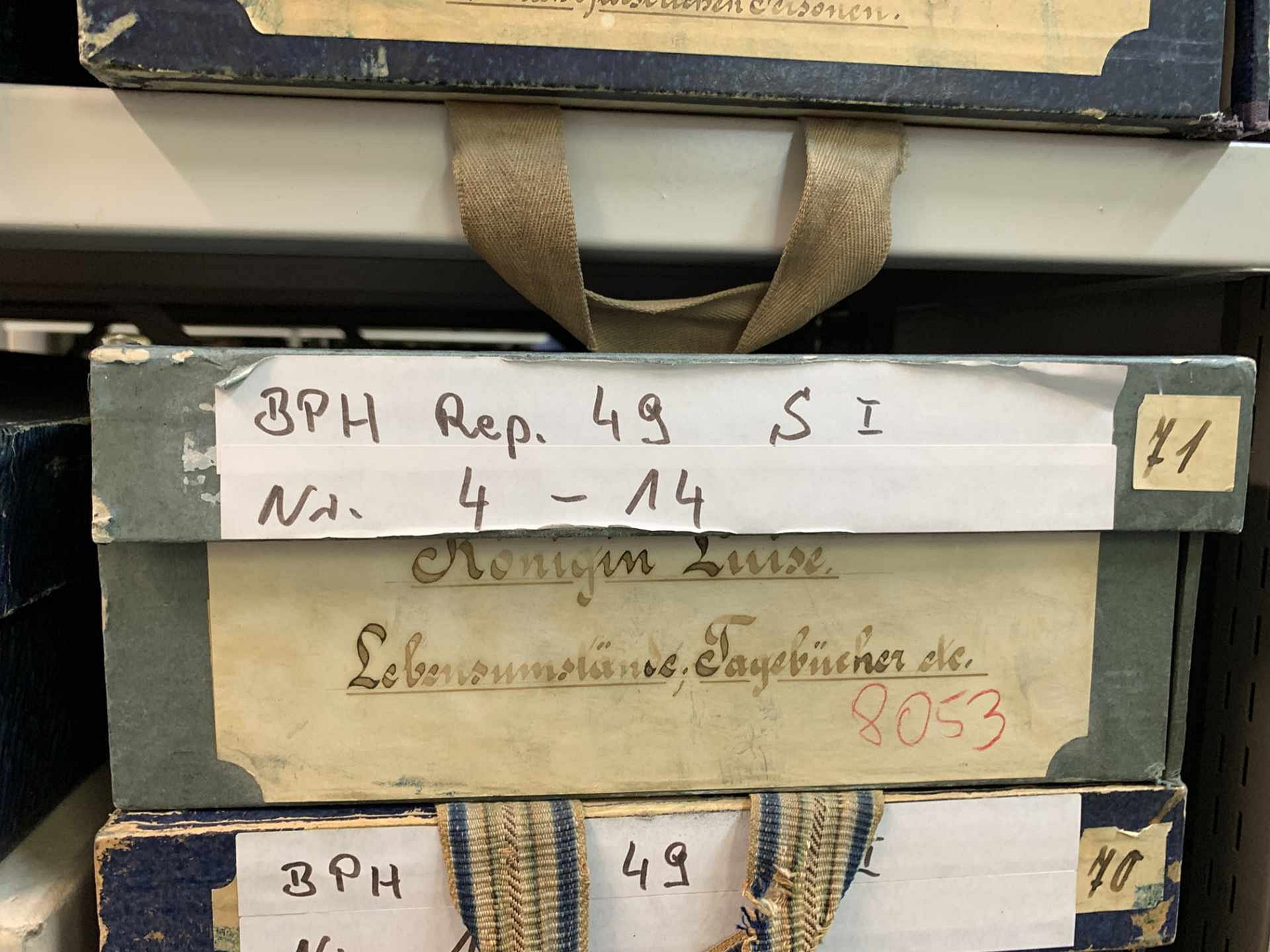 Eine beschriftete Pappschachtel in einem Regal.