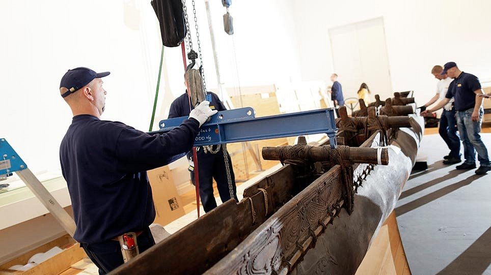 Mehrere Menschen bereiten ein hölzernes Boot zum Transport vor (öffnet Vergrößerung des Bildes)