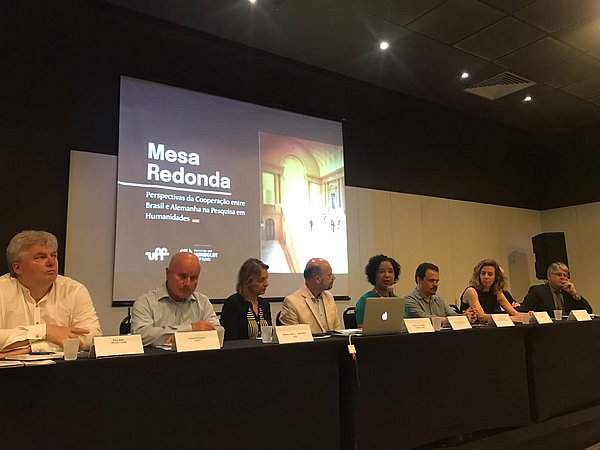 Roundtable Menschen auf einem Podium an einem langen Tisch
