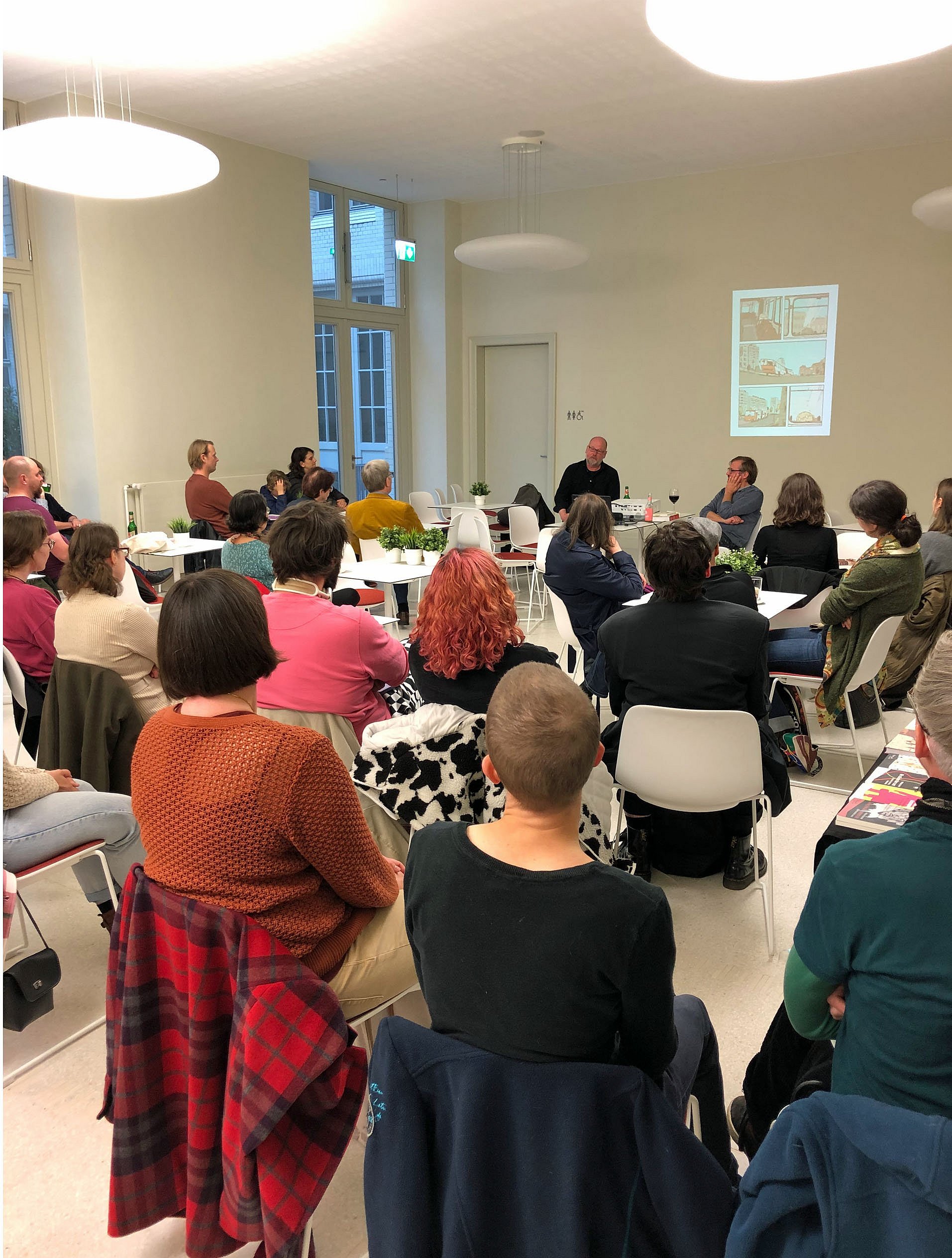 Menschen sitzen auf Stühlen und schauen auf ein Podium
