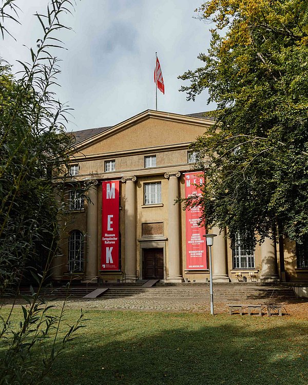 MEK in der Arnimallee Museumsfassade mit zwei roten Bannern