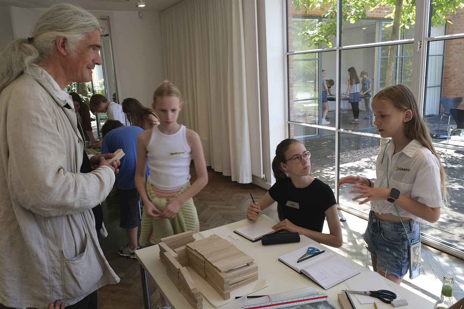 Personengruppe an einem Tisch diskutiert über Architekturmodelle