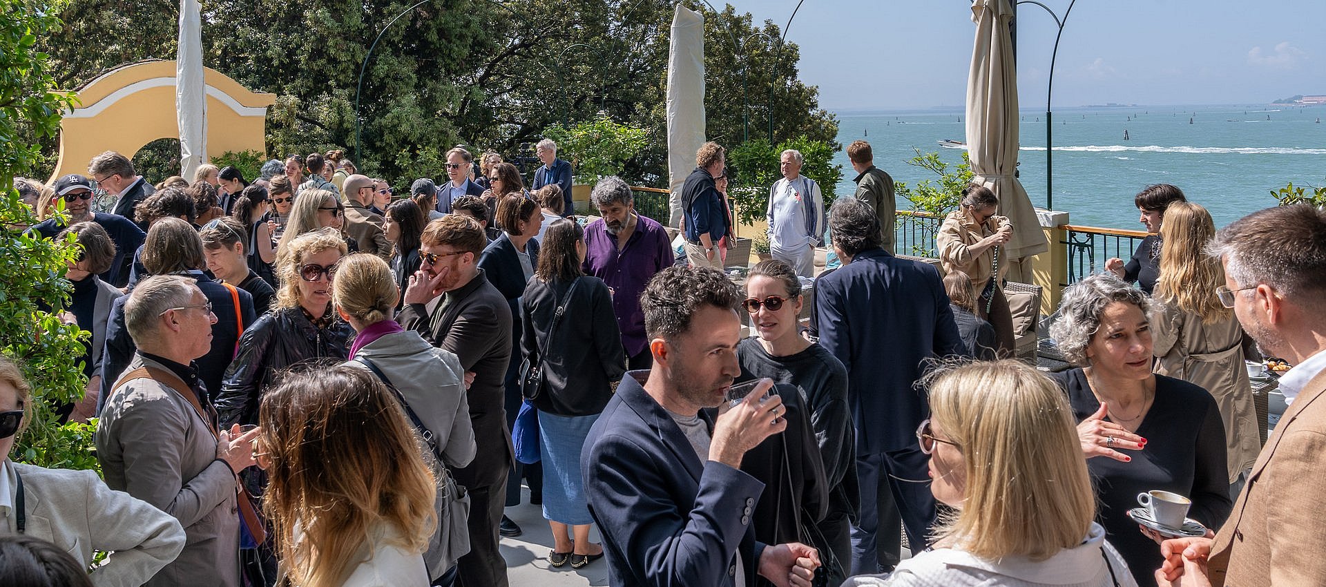 Berlin Breakfast zur Kunstbiennale in Venedig Mehrere Gäste applaudieren während einer Veranstaltung auf einer Terrasse in Venedig.