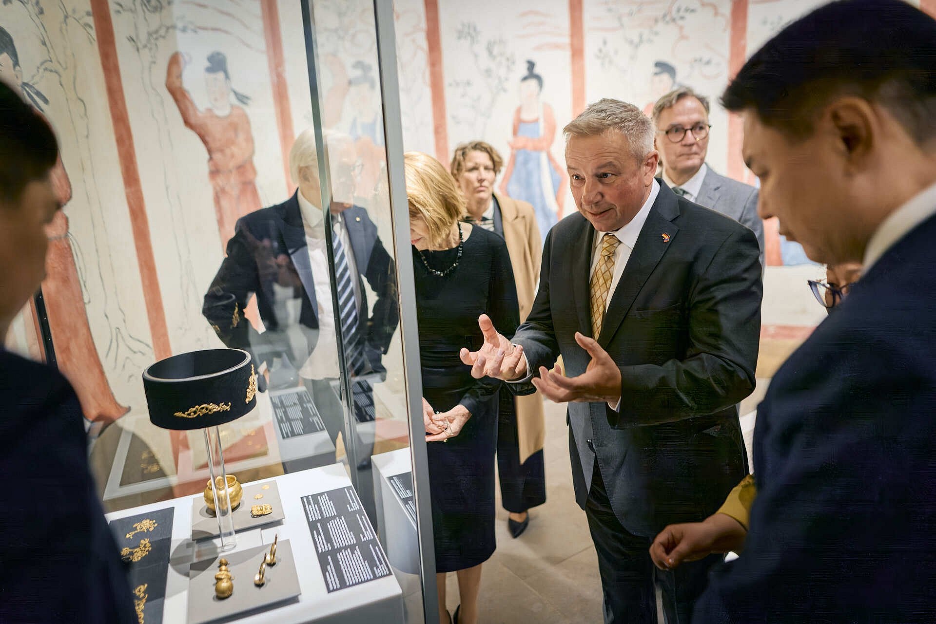 Eine Gruppe betrachtet bei einer Führung Ausstellungsstücke in einer beleuchteten Vitrine.