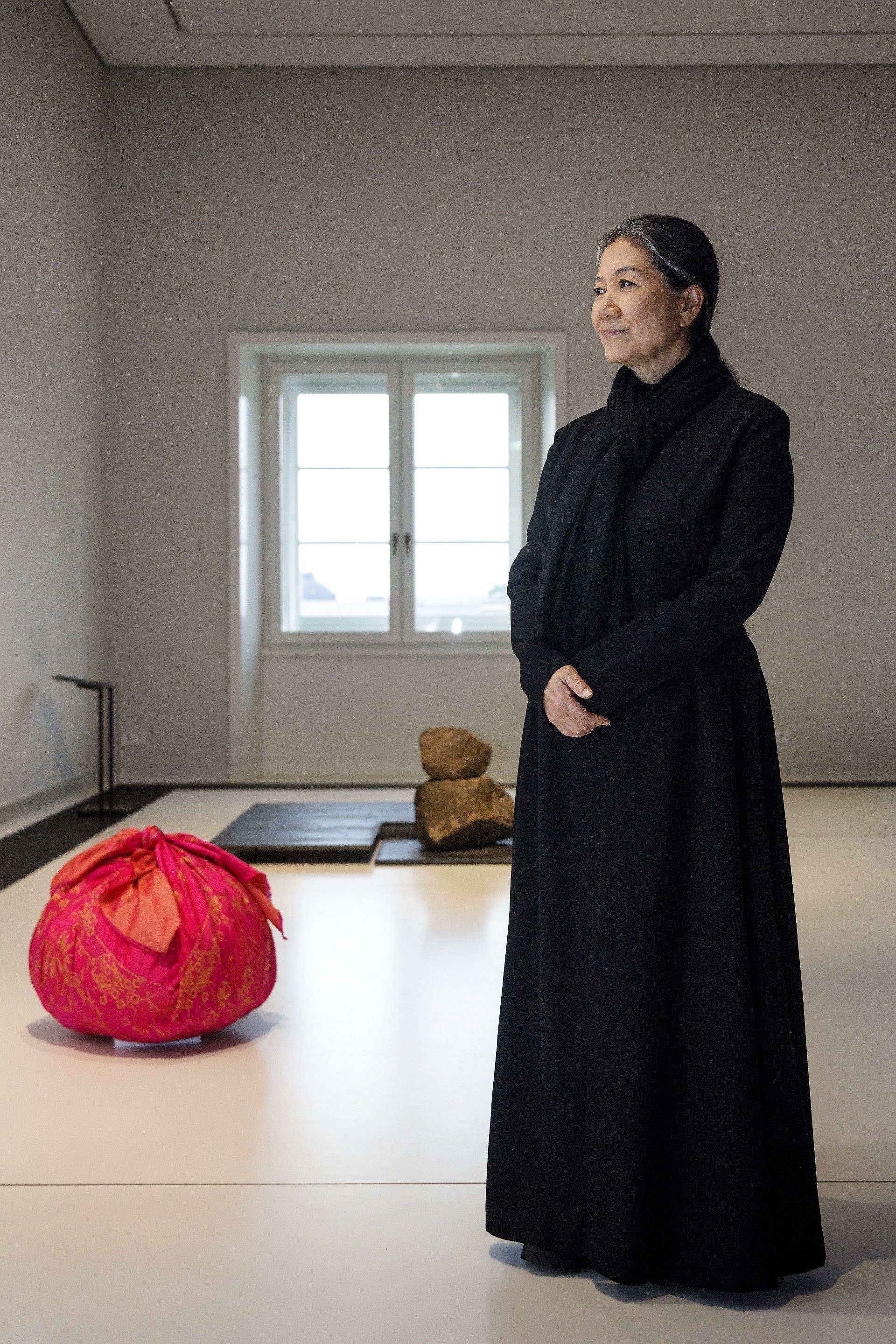 Fotografie einer in schwarz gekleideten, mittelalten Frau in einem Ausstellungsraum