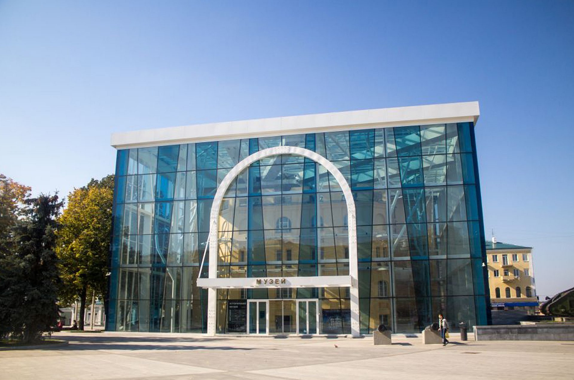 Gläserner Museumsbau vor blauem Himmel