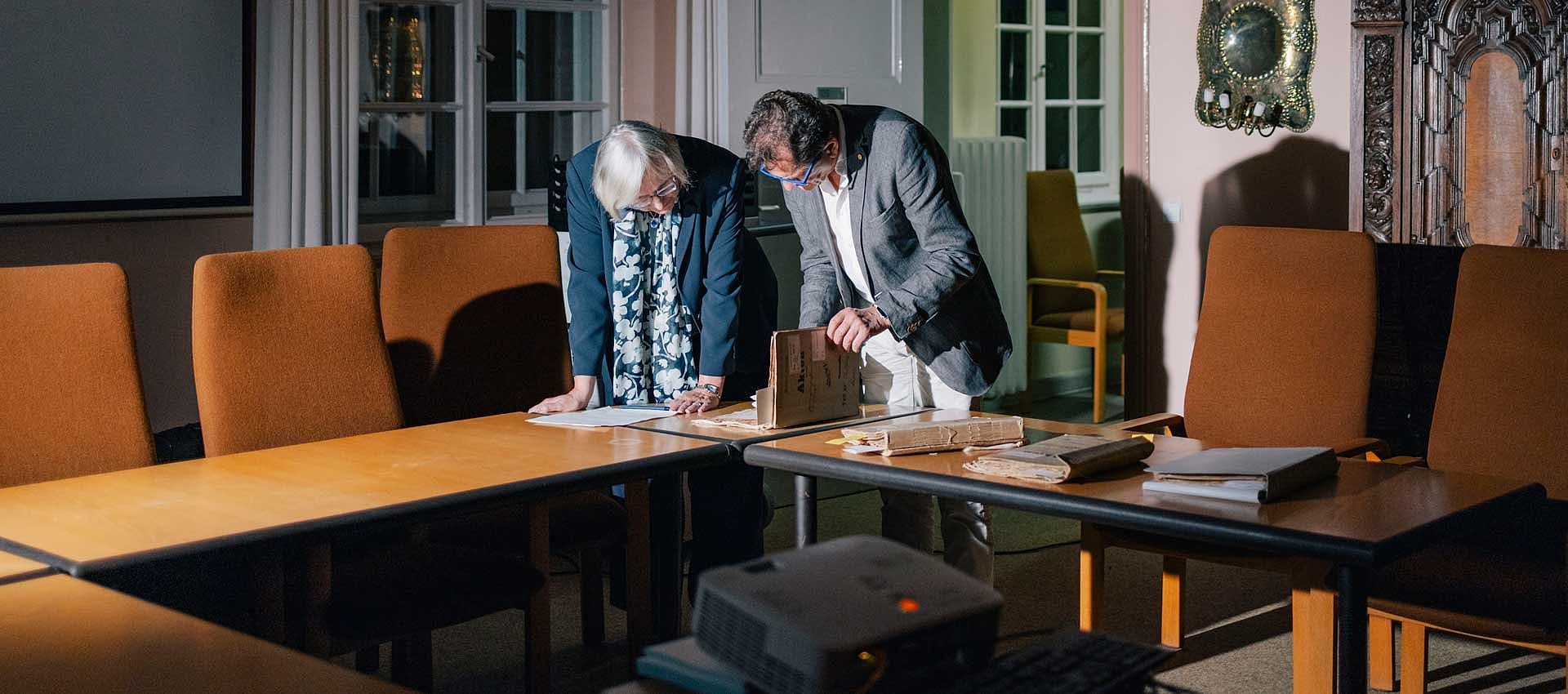 Zwei Personen beugen sich über Akten auf dem Tisch