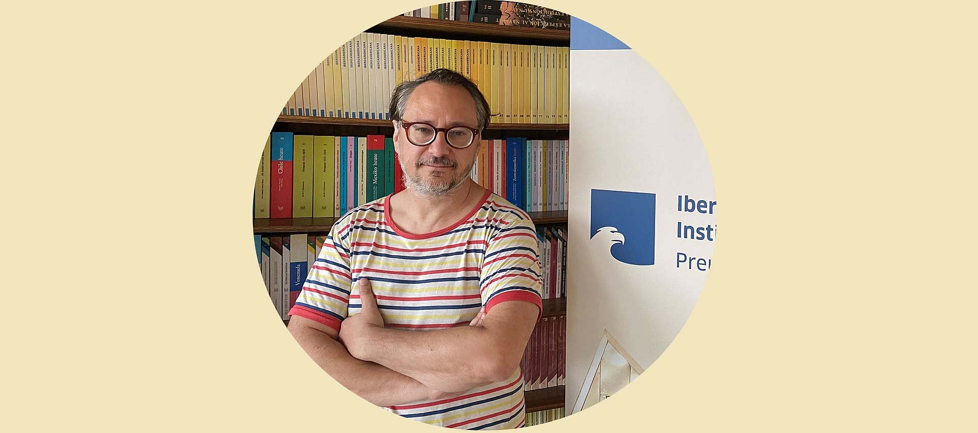 Porträt eines Mannes neben einem Aufsteller vor Bücherregal