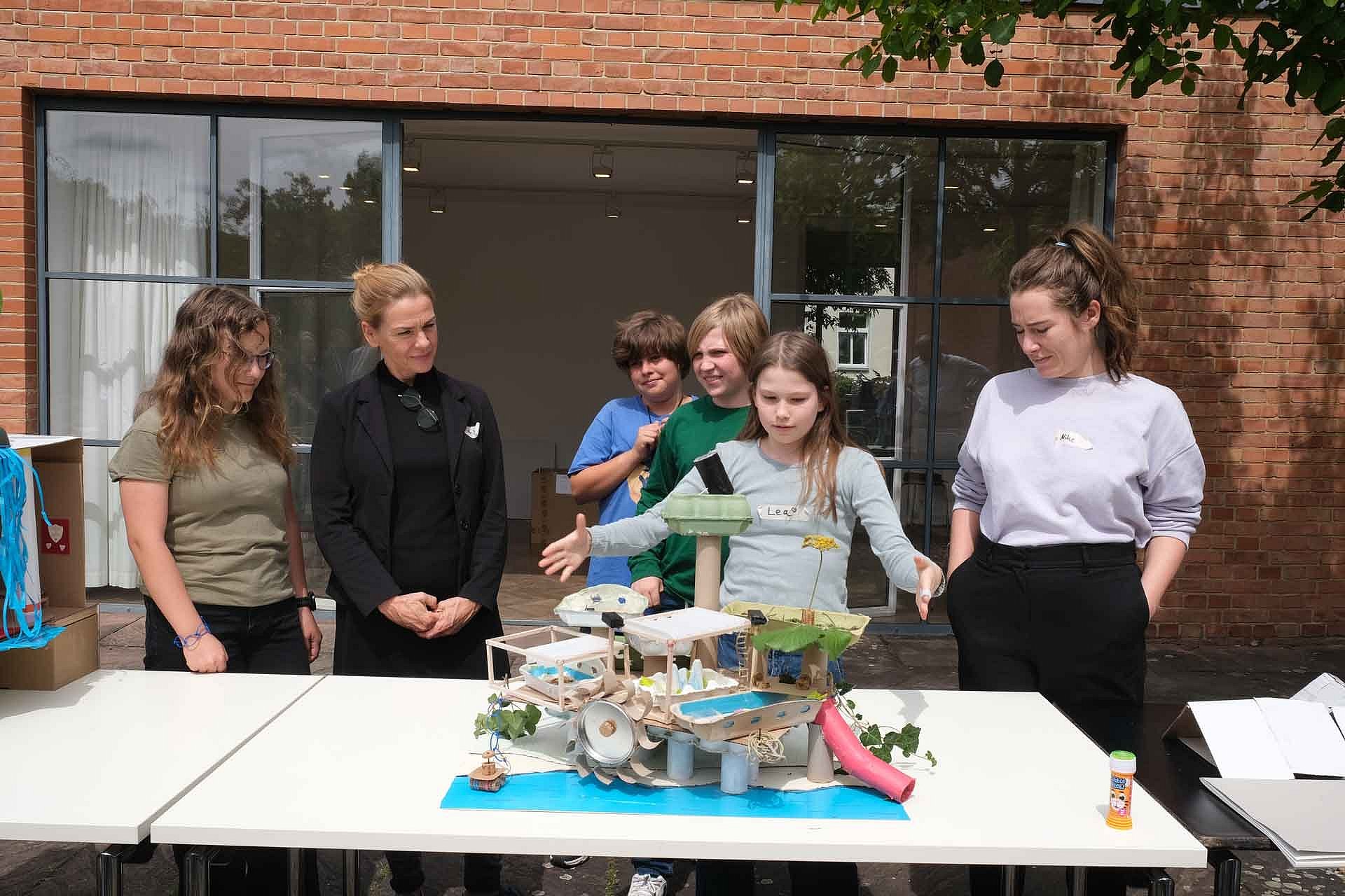 Kinder zeigen ihr Architekturmodell auf einem Tisch